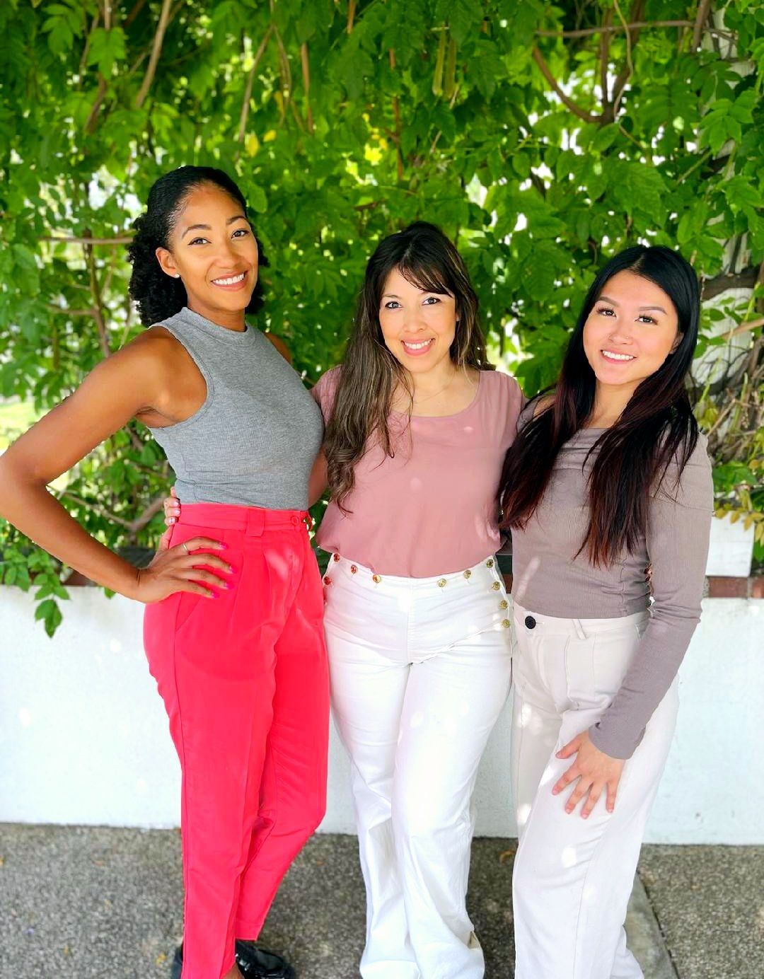 Three women are posing for a picture together in front of a tree.