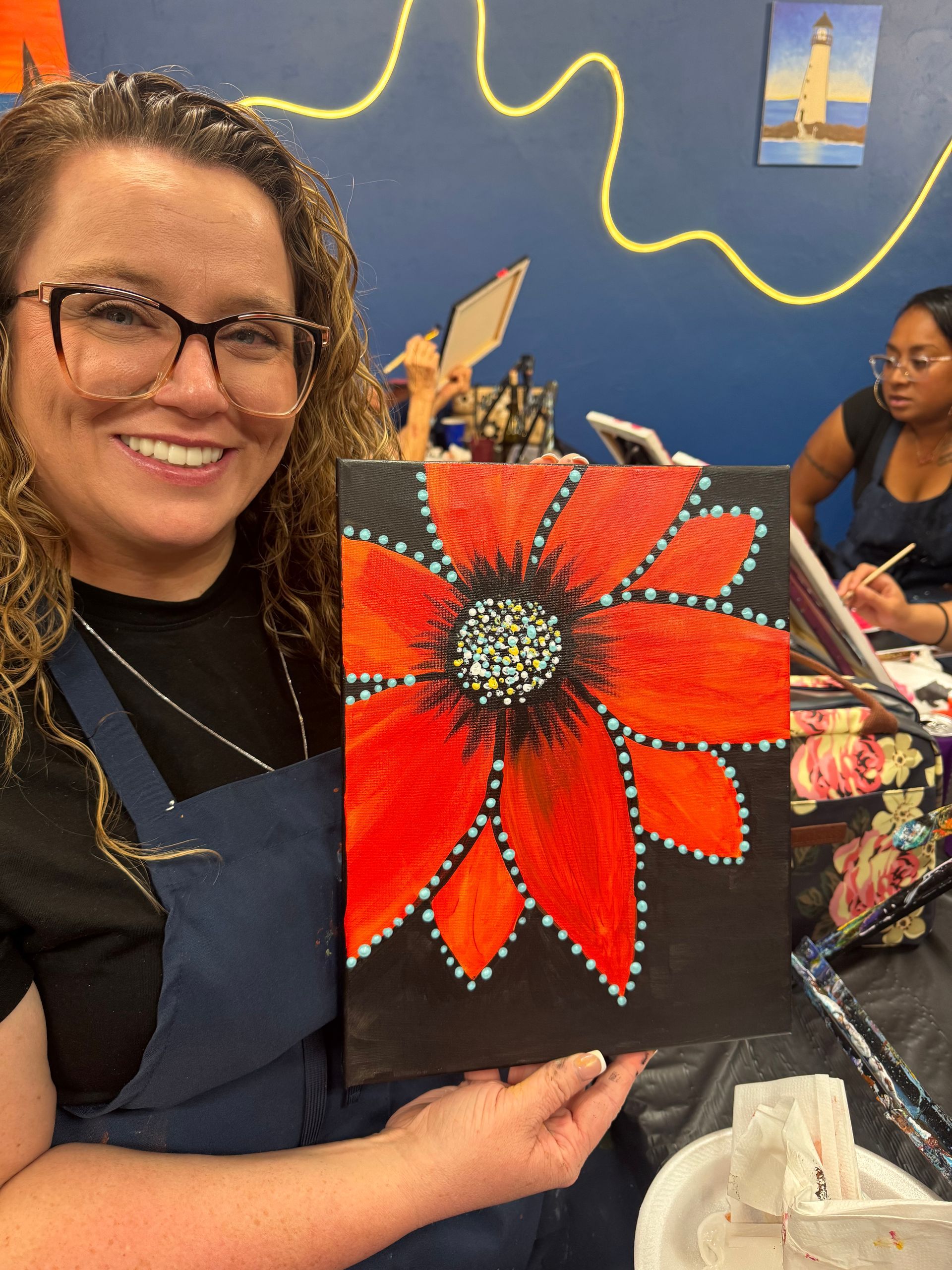 A woman wearing glasses and a floral kimono is smiling in front of a tree.