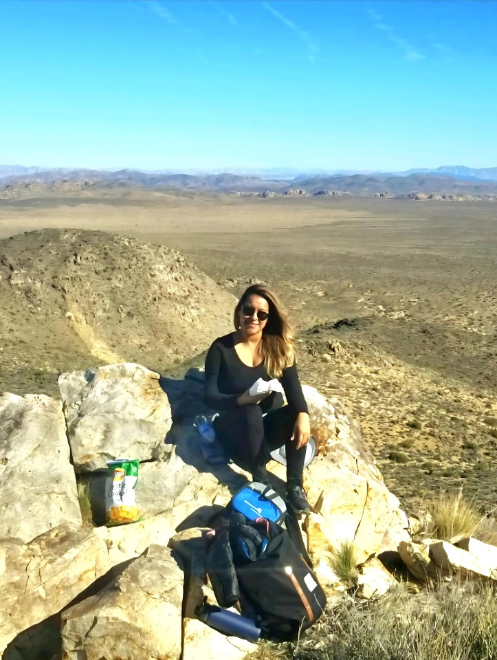 A woman is sitting on a rock in the desert