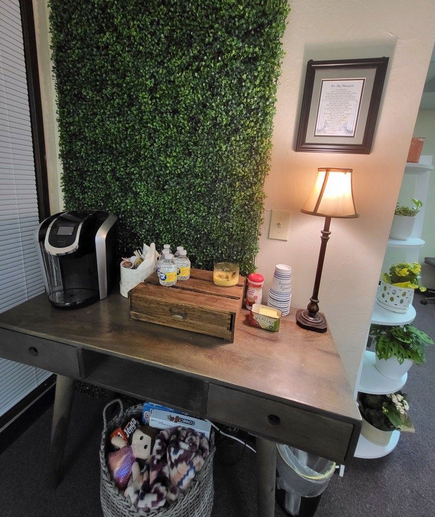 A desk with a lamp and a coffee maker on it in a room.
