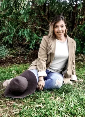 A woman is sitting on the grass with a hat.