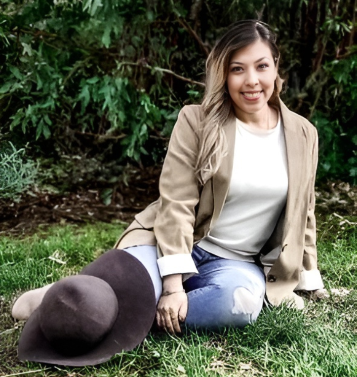 A woman is sitting on the grass with a hat.