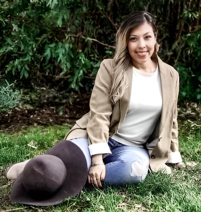 A woman is sitting on the grass with a hat.