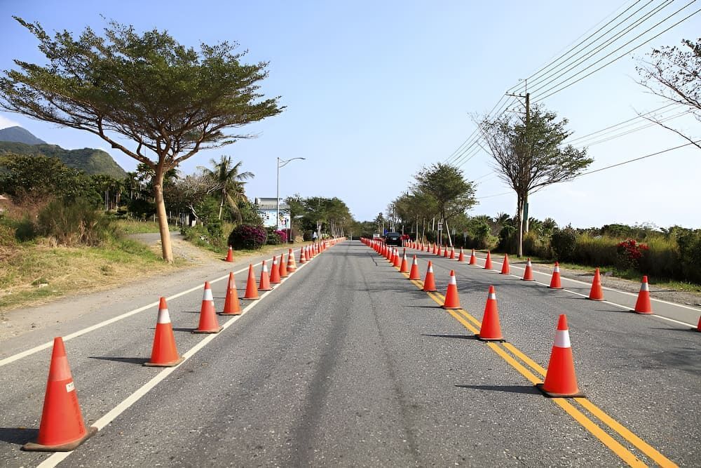 A Row Of Orange Traffic Cones On The Side Of A Road — S & K Raw Materials & Earthmoving in Normanton, QLD