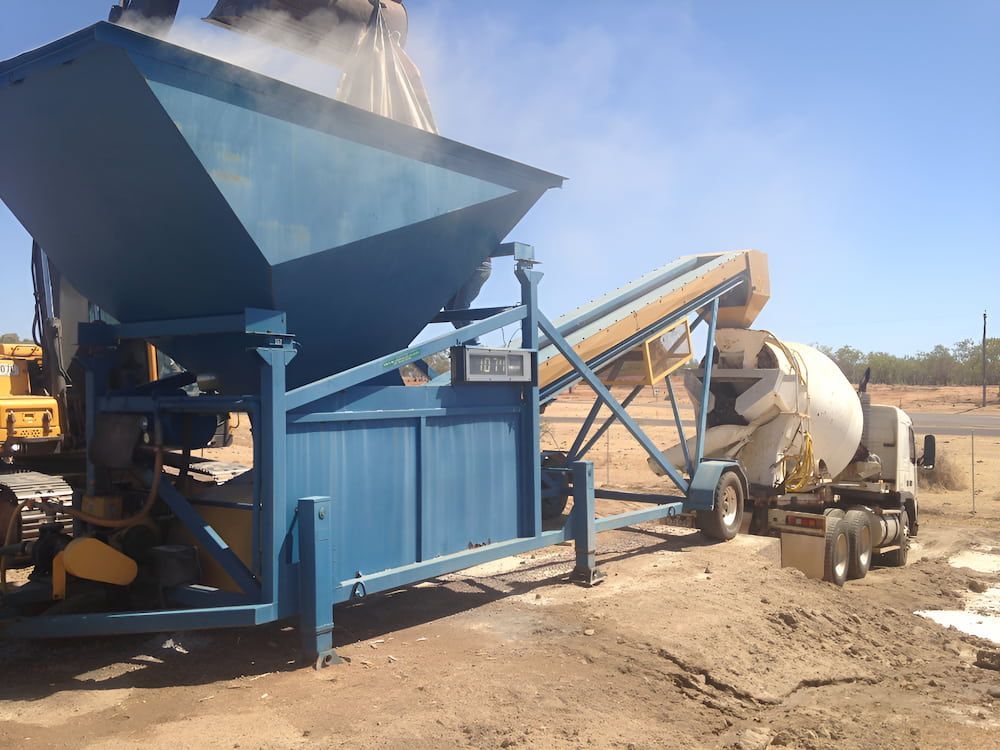 A Concrete Mixer Is Pouring Concrete Into A Blue Container — S & K Raw Materials & Earthmoving in Atherton, QLD