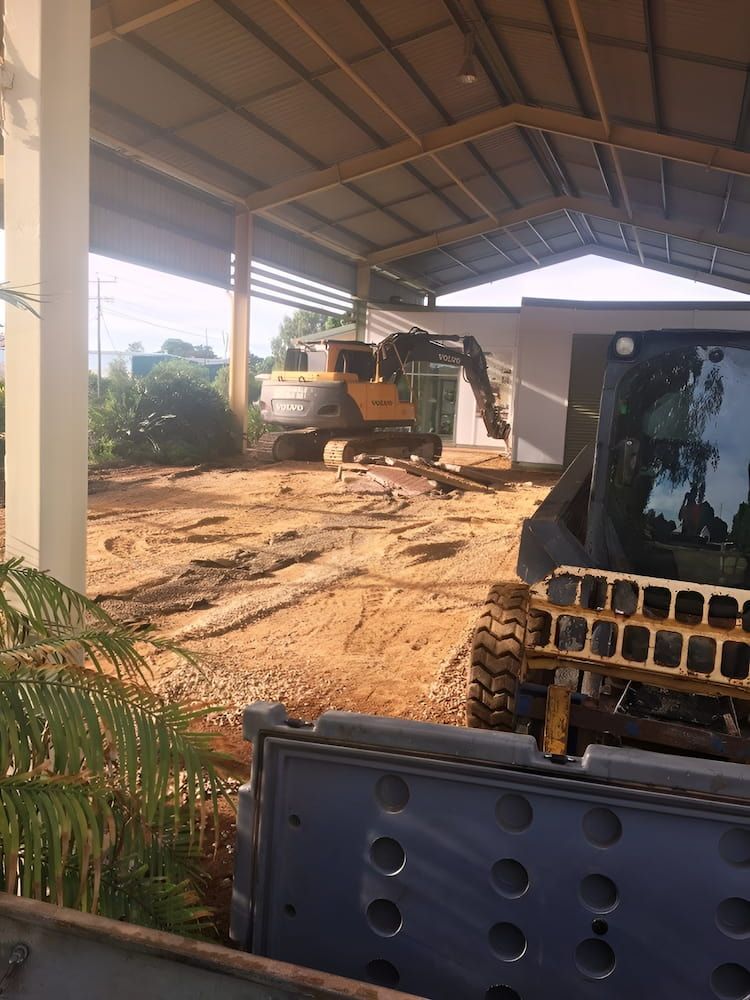 A Bulldozer Is Sitting In The Dirt Under A Roof — S & K Raw Materials & Earthmoving in Georgetown, QLD