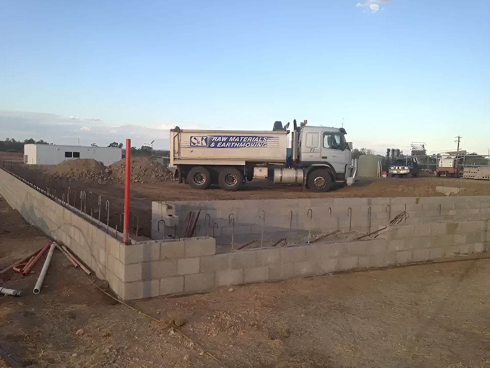 A Dump Truck Is Parked Next To A Brick Wall — S & K Raw Materials & Earthmoving in Atherton, QLD