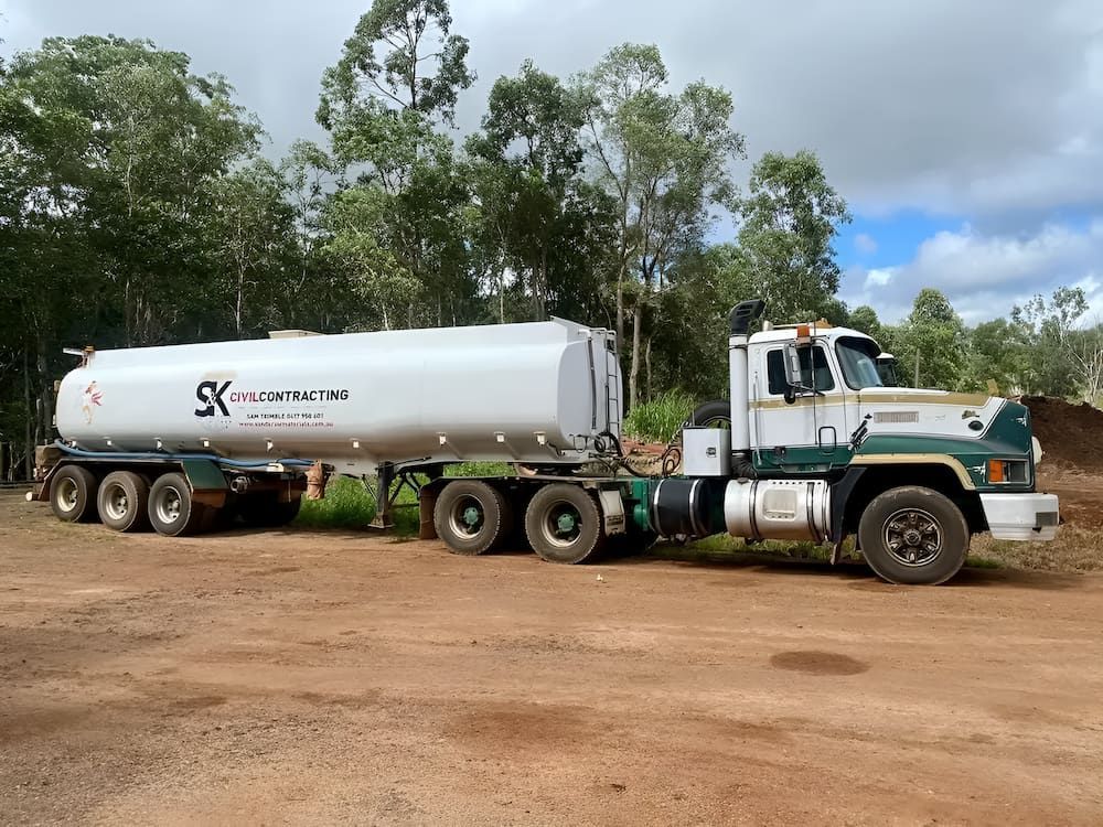 A Tanker Truck With A Trailer Attached To It Is Parked In A Dirt Lot — S & K Raw Materials & Earthmoving in Atherton, QLD