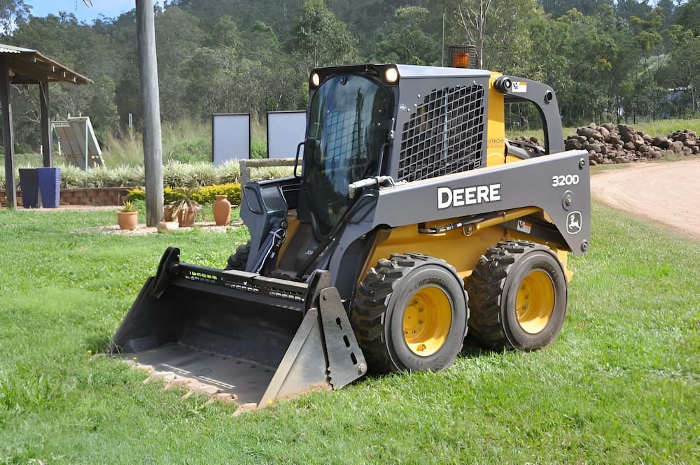 A Deere Skid Steer Is Parked In A Grassy Field — S & K Raw Materials & Earthmoving in Normanton, QLD