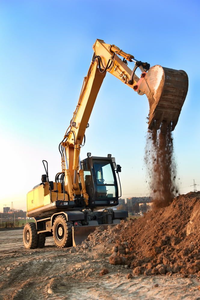 A Yellow Excavator Is Digging A Pile Of Dirt On A Construction Site — S & K Raw Materials & Earthmoving in Atherton, QLD