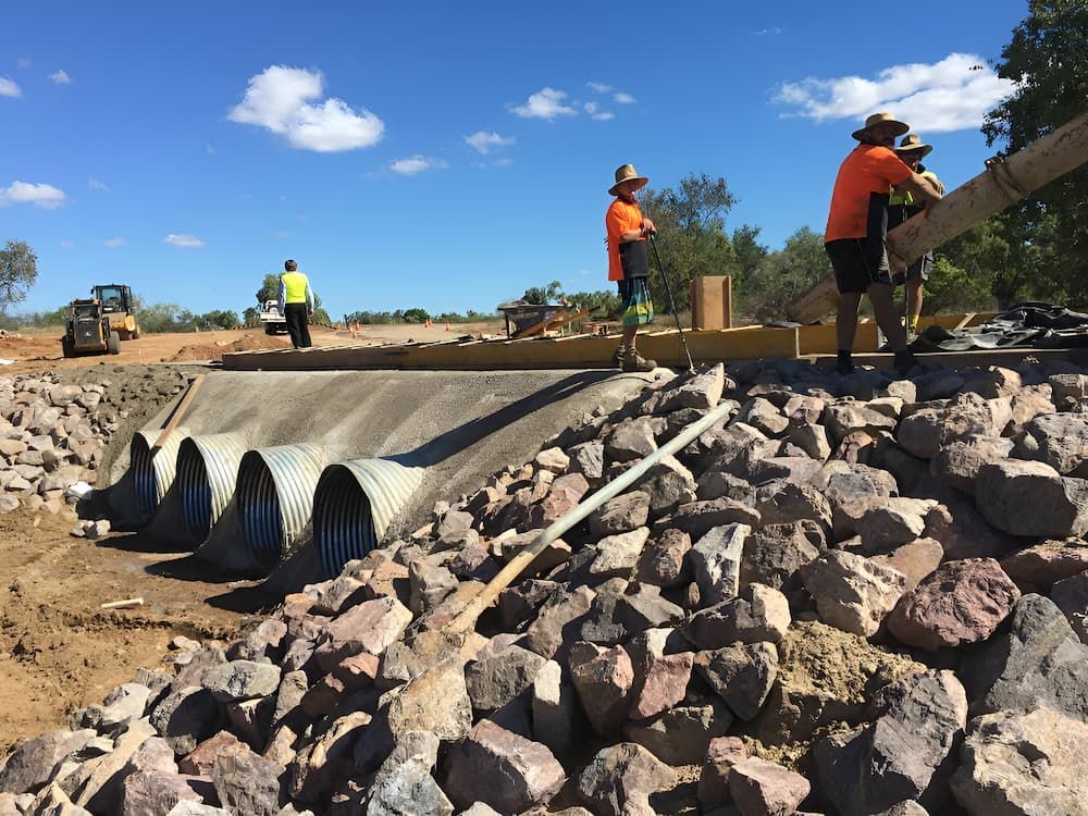 A Group Of Construction Workers Are Working On A Road — S & K Raw Materials & Earthmoving in Atherton, QLD