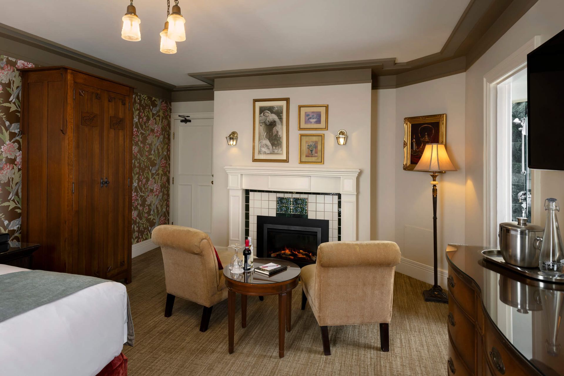 A hotel room with a fireplace and two chairs