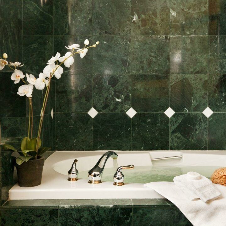 A bathtub in a bathroom with green tiles