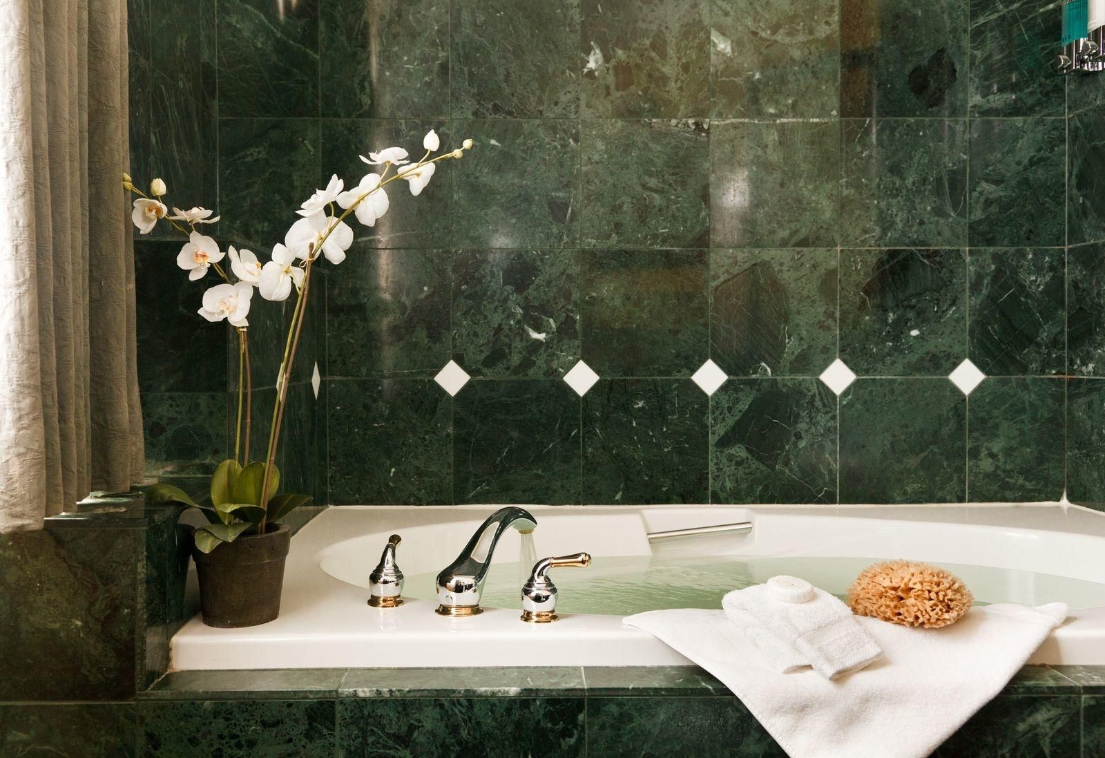 A bathtub in a bathroom with green tiles
