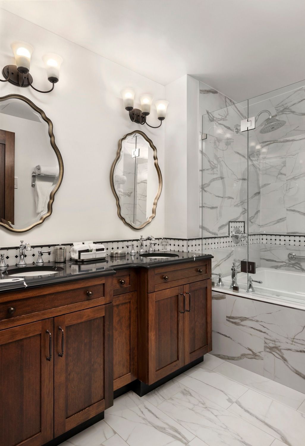 A bathroom with two sinks , two mirrors and a bathtub.
