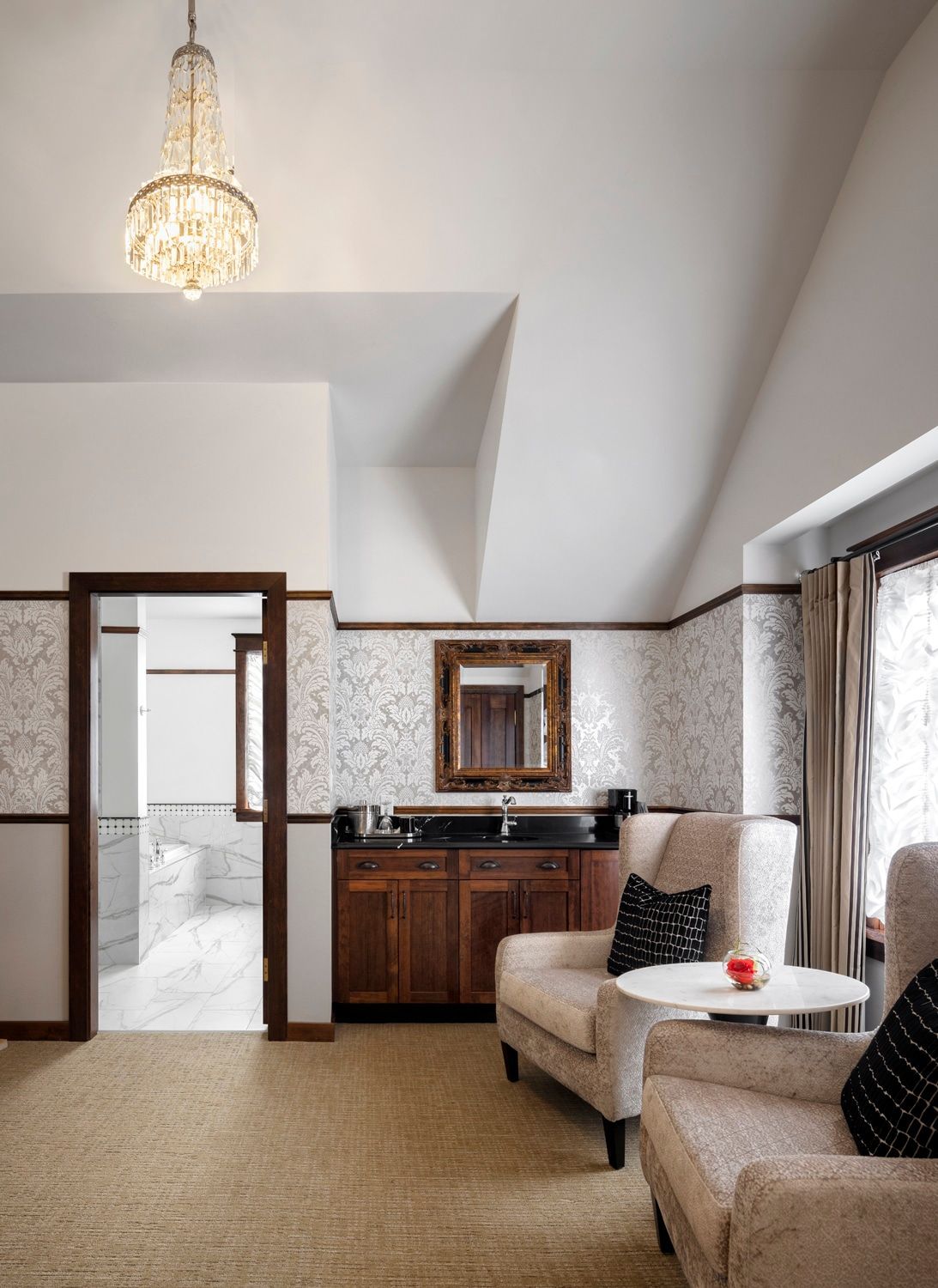 A living room with two chairs a table and a mirror