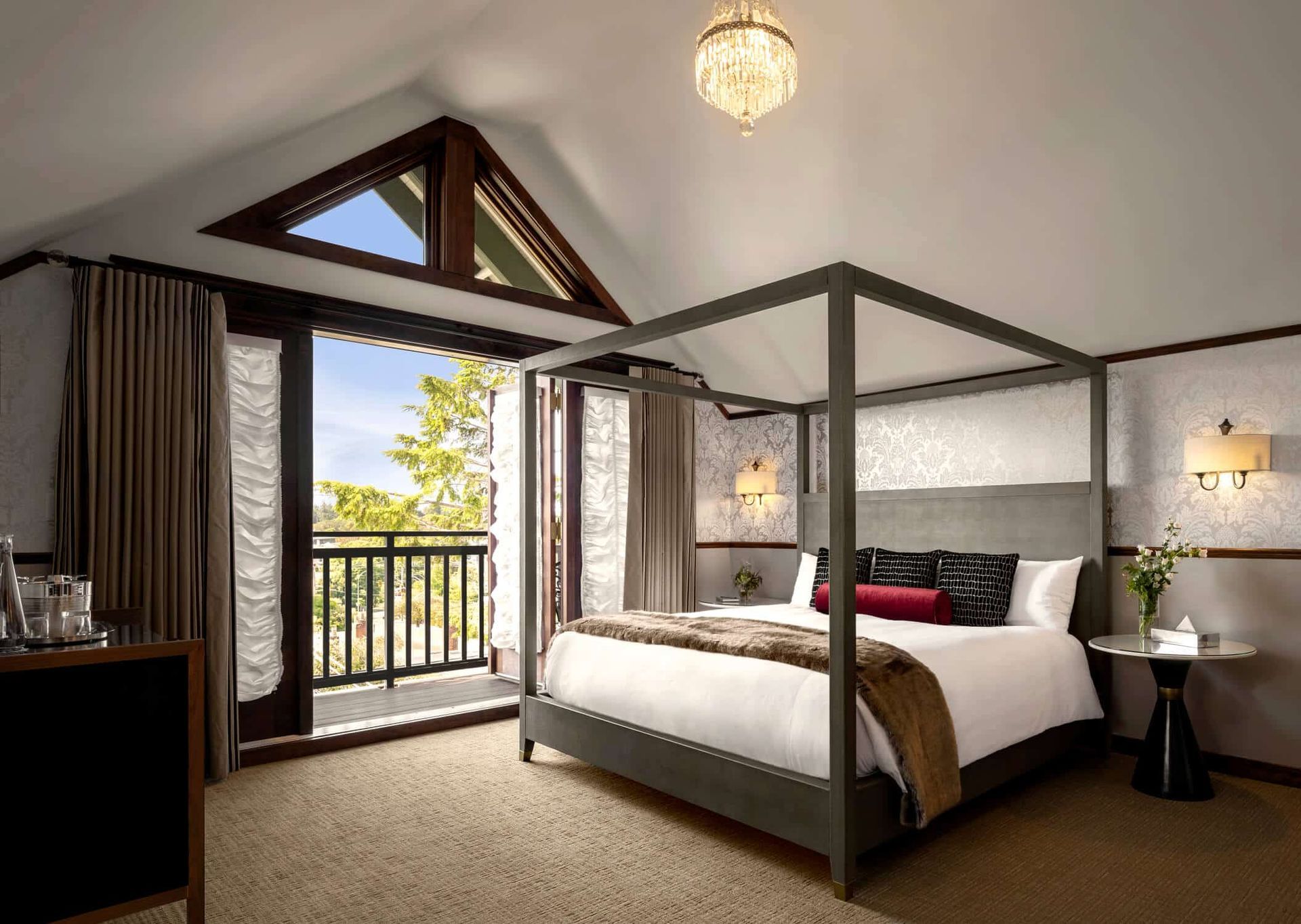 A hotel room with a four poster bed and a balcony