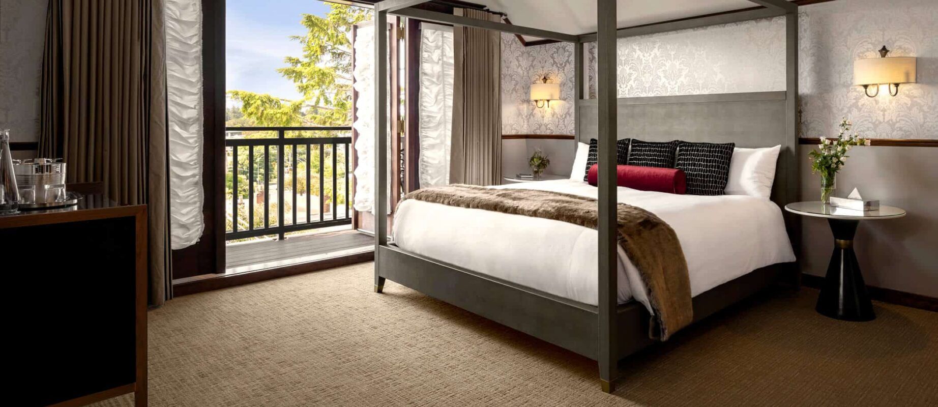 A hotel room with a four poster bed and a balcony.