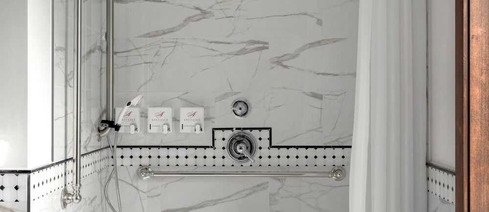 A bathroom with marble tiles and a shower curtain.