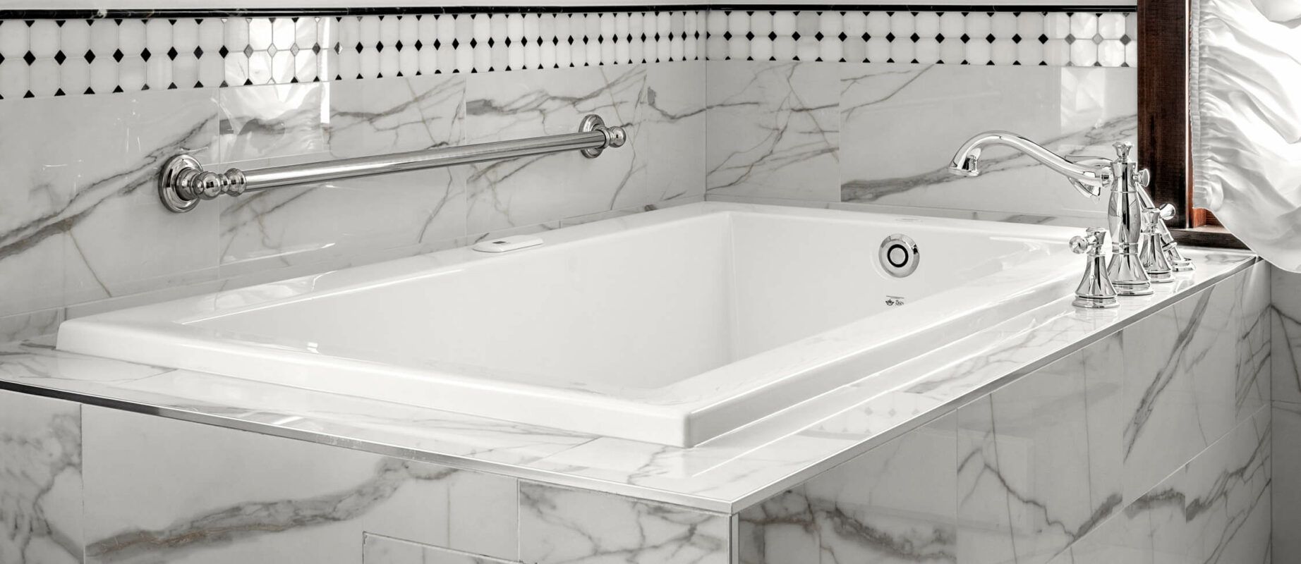 A white bathtub is sitting on top of a marble counter in a bathroom.
