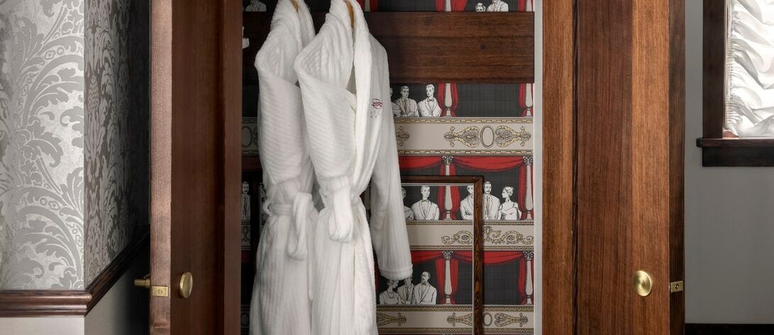 A white robe is hanging in a wooden closet.