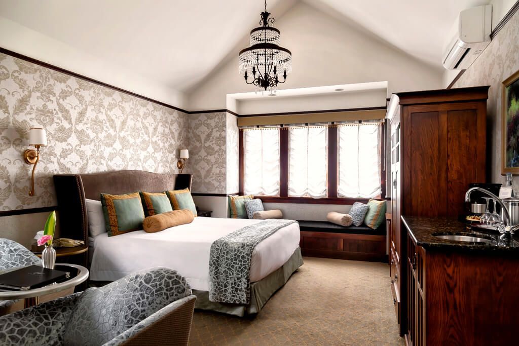 A hotel room with a king size bed and a chandelier