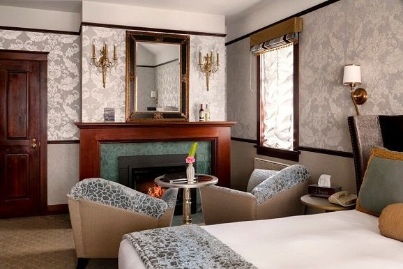 A hotel room with a fireplace and two chairs
