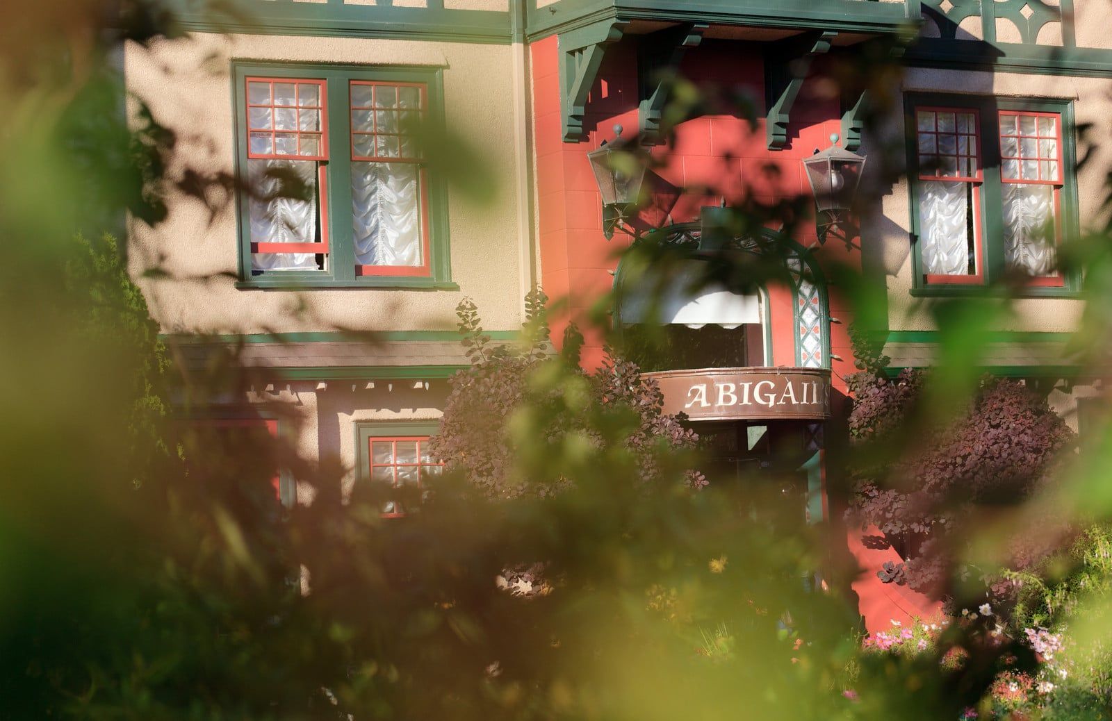 A house with a sign on the side of it is surrounded by trees.