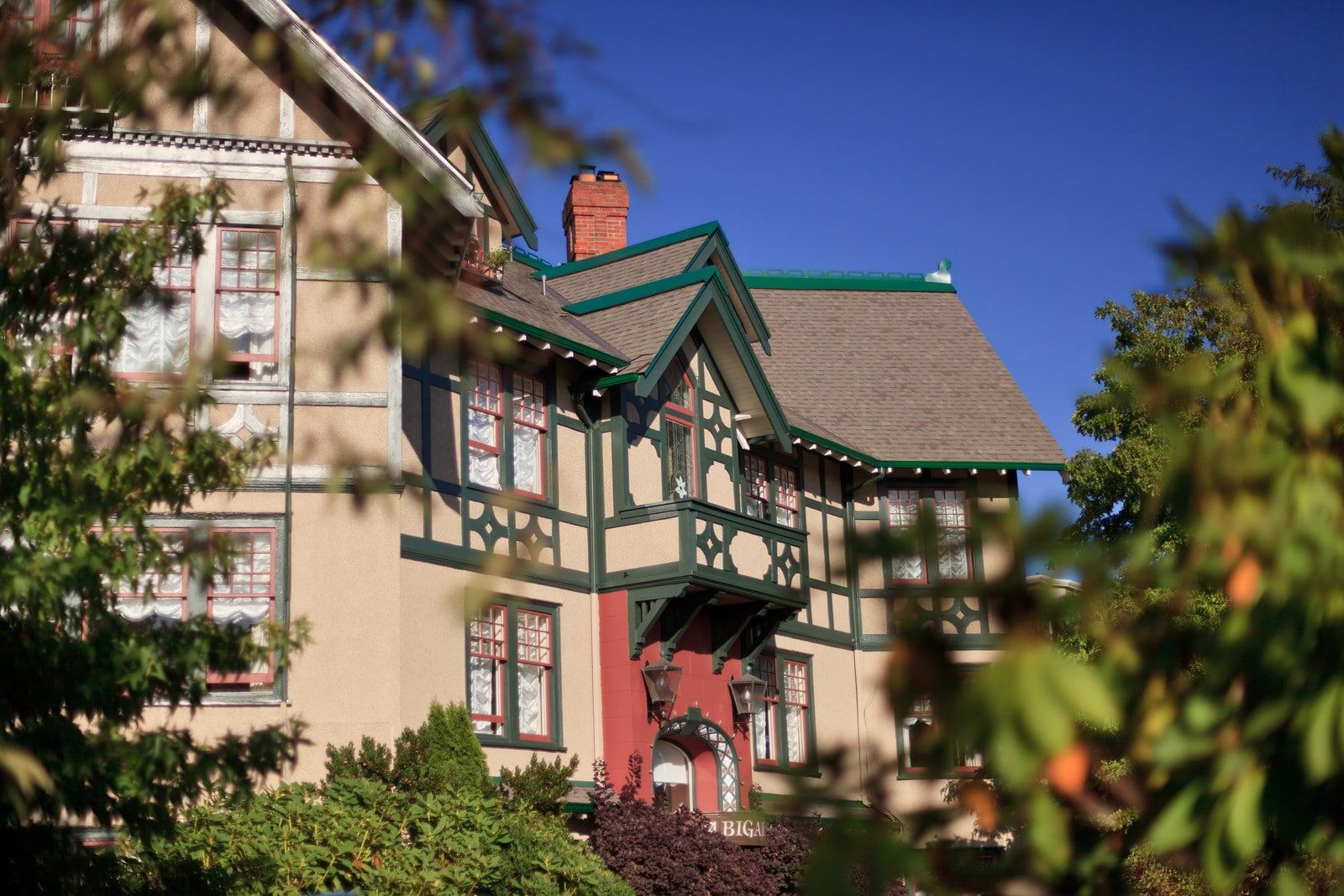 A large house is surrounded by trees on a sunny day