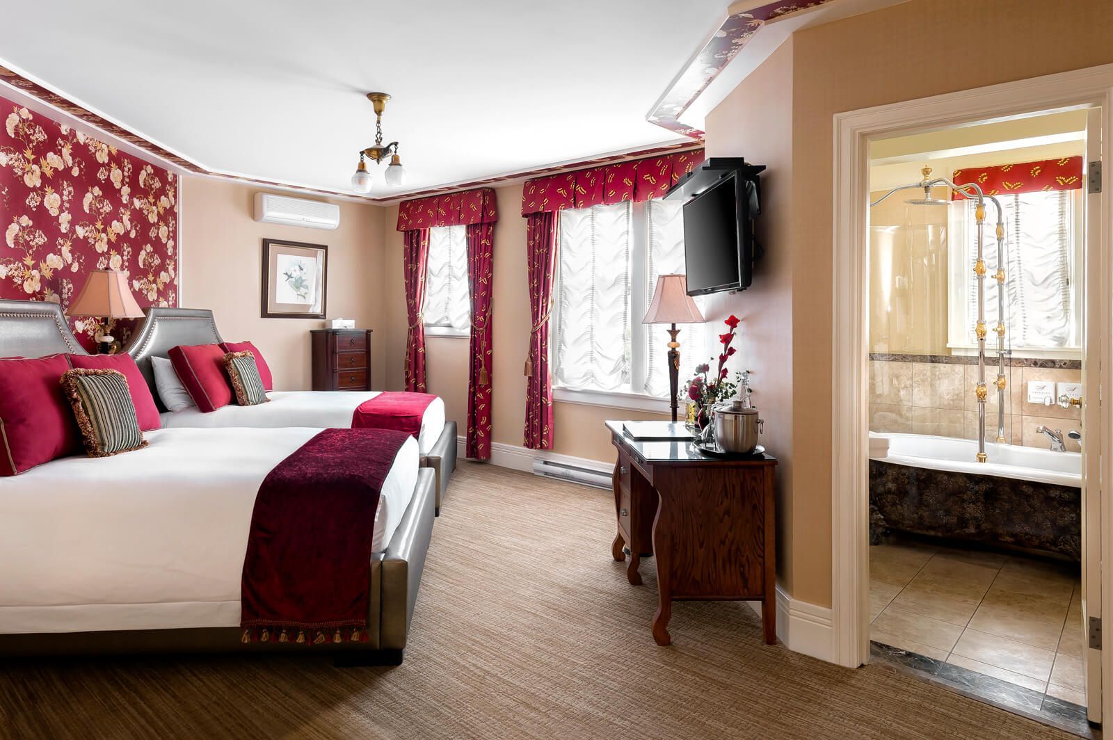 A hotel room with two beds , a desk , a television and a bathtub.