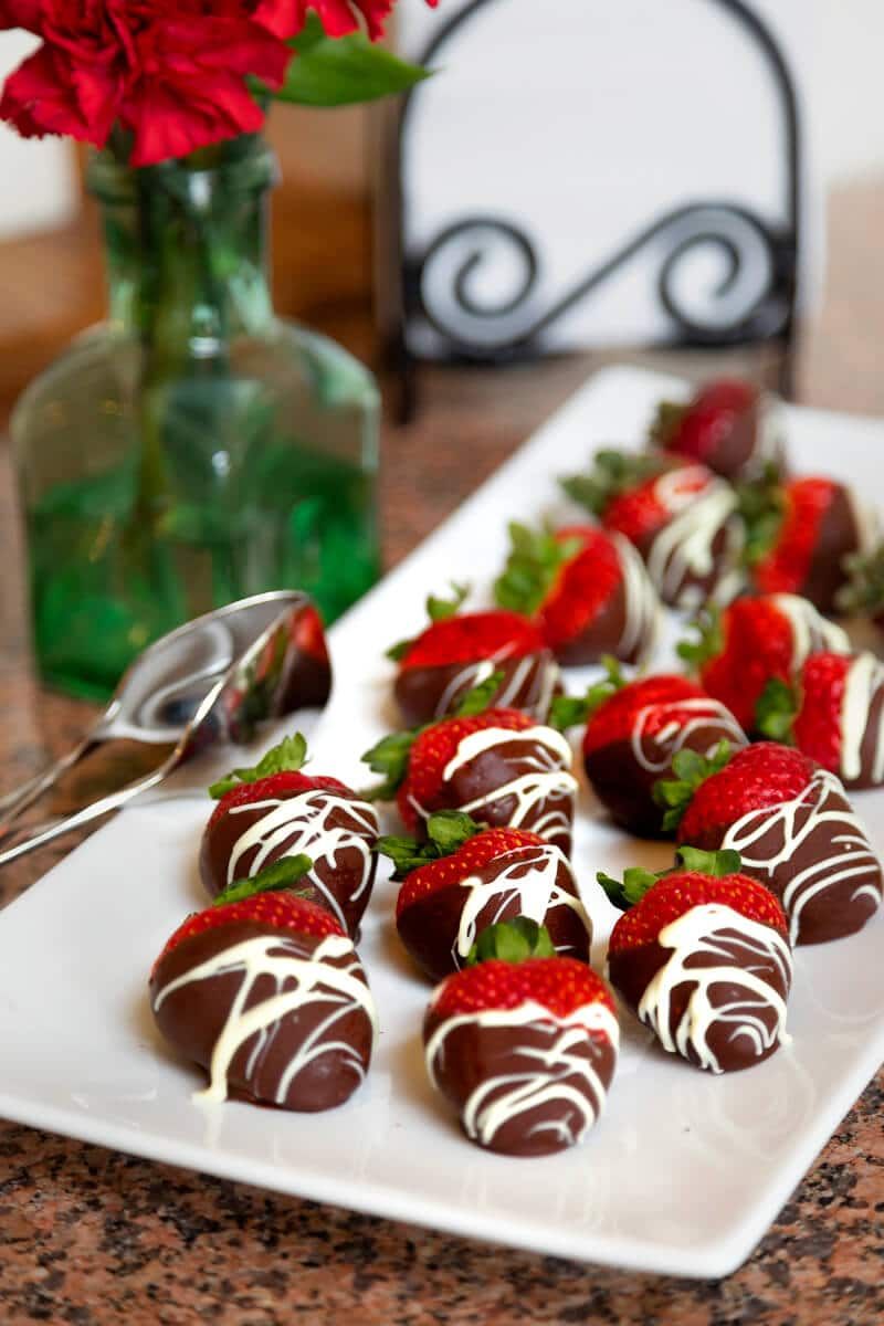 A white plate topped with chocolate covered strawberries