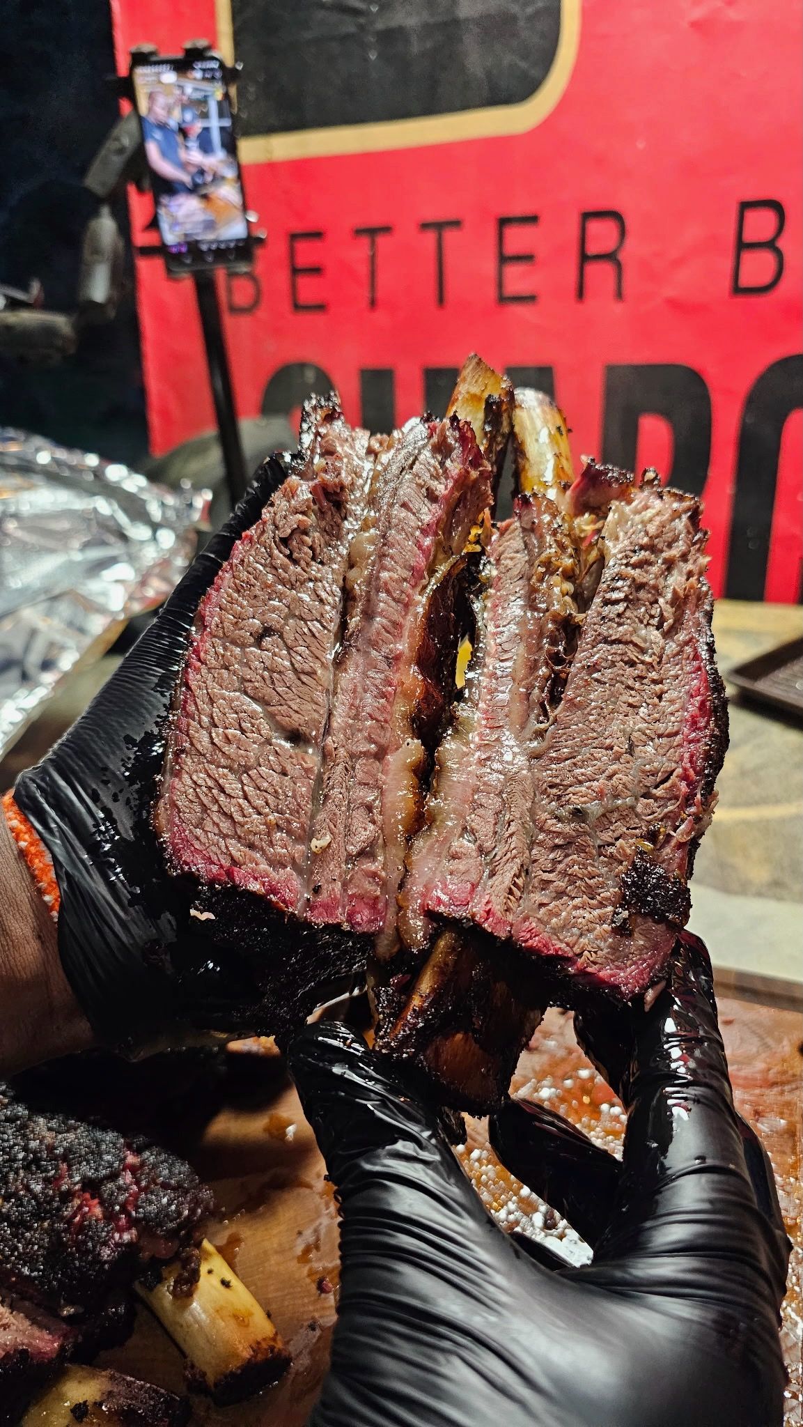 gloved hands holding sliced, smoked beef dino ribs with a visible smoke ring.