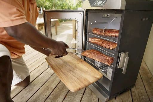 Man removing ribs from electric smoker