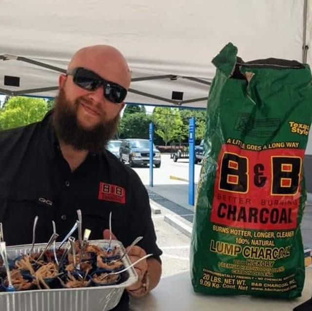 Wes Phillips, Pitmaster of Burnt Bermuda BBQ, with grilled food and B&B Hickory Lump Charcoal