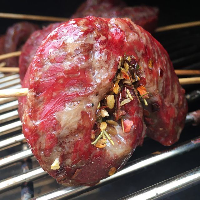 Skewers of steak rolled with spices cooking on the grill