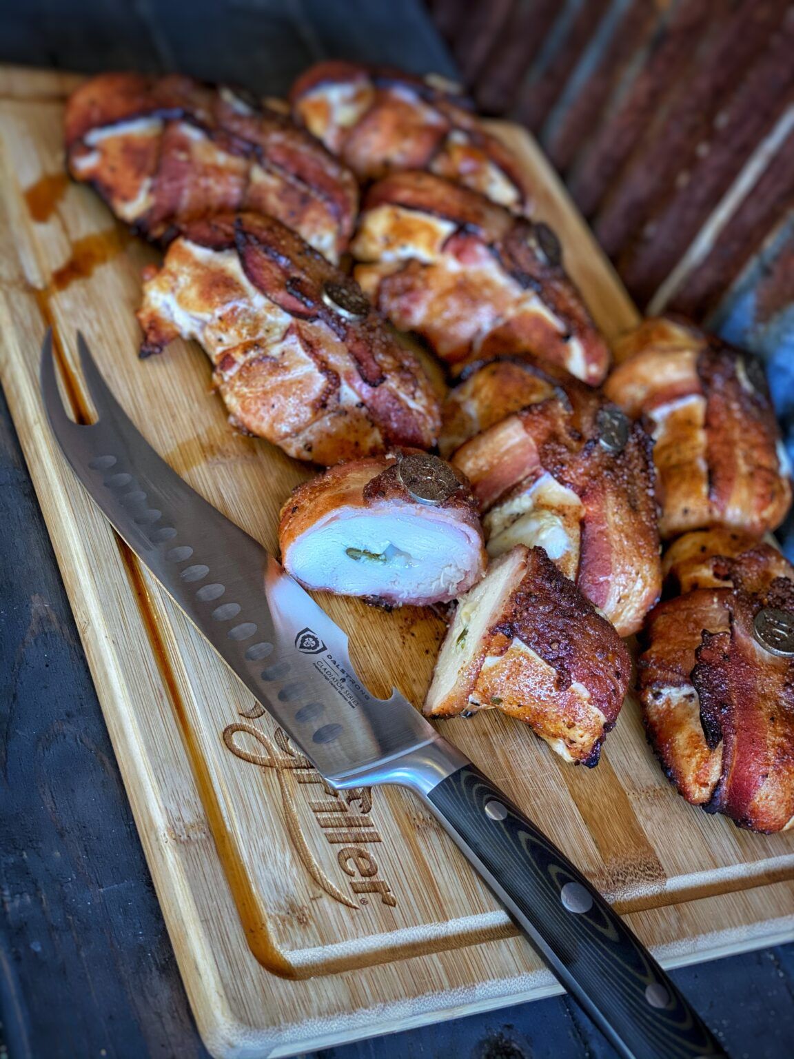 bacon-wrapped grilled chicken with jalapenos and cheese sliced on cutting board with a knife