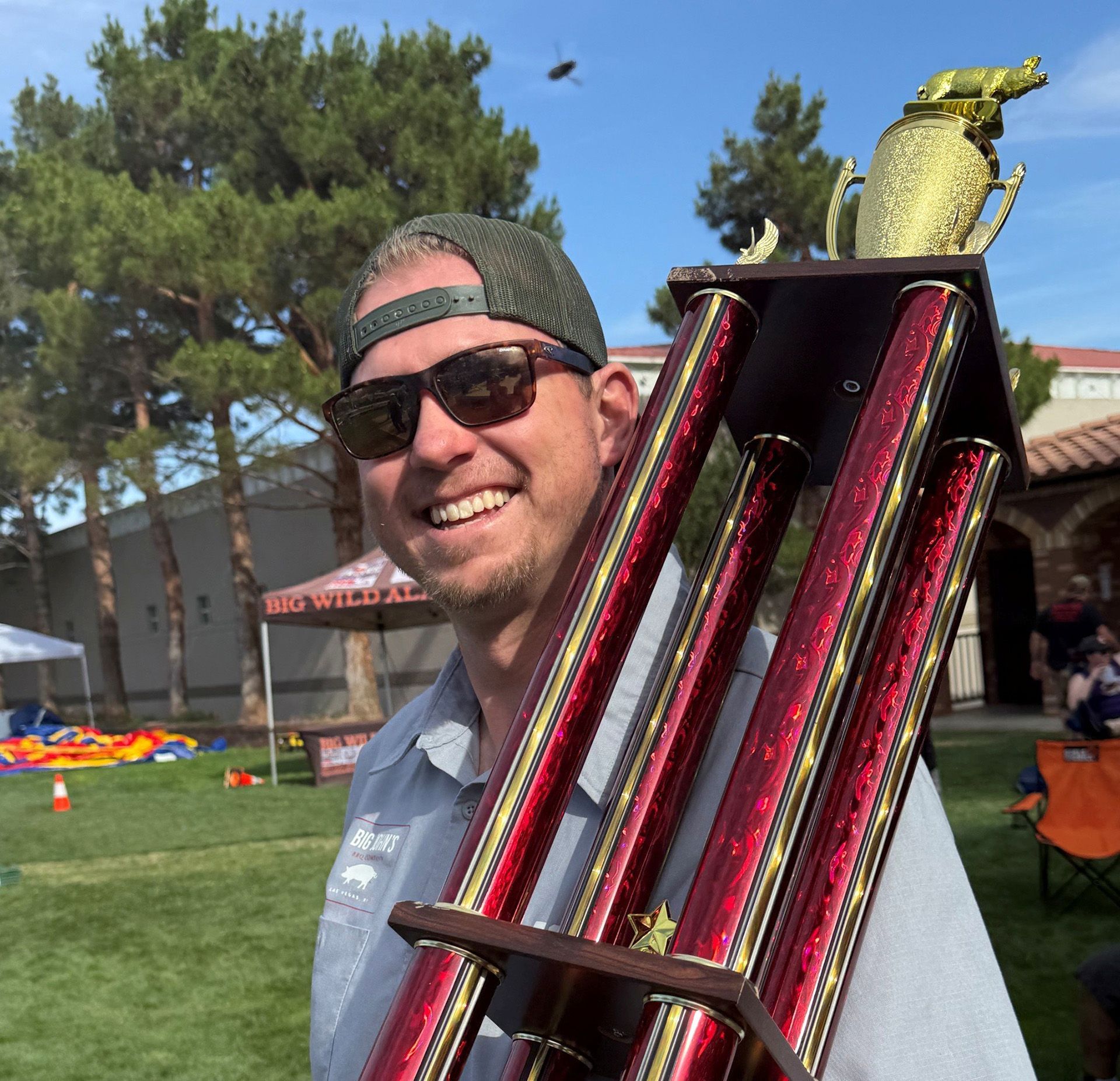 John Bowman B&B pitmaster holding a large red trophy 