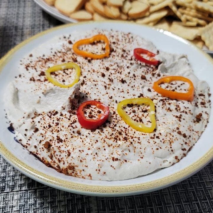 Smoked fish dip in a bowl garnished with spices and peppers