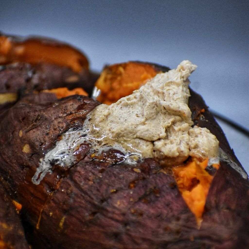 Closeup of a grilled sweet potato with a generous dollop of maple cinnamon butter