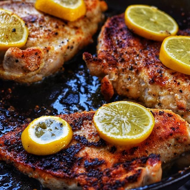 herb crusted chicken in cast iron pan with lemon slices