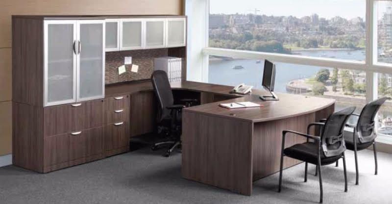An office with a desk , chairs , cabinets and a large window.