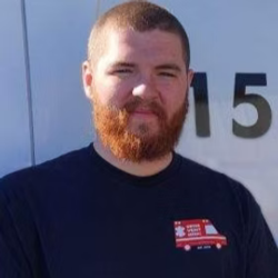 A man with a beard is standing in front of a van with the number 15 on it.
