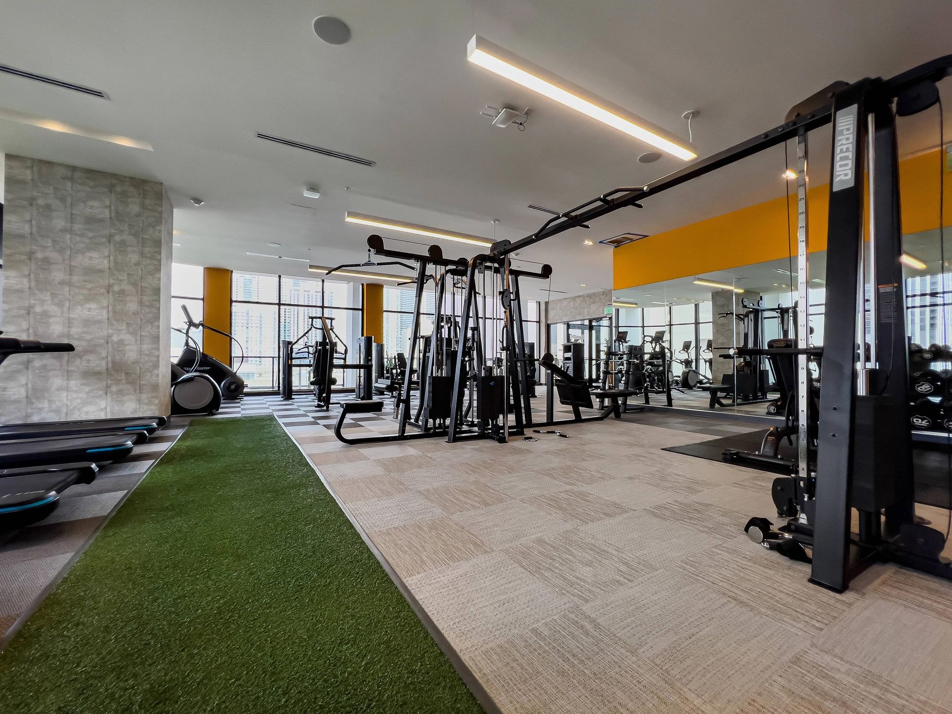 Gym interior with exercise machines, turf, and mirrors.