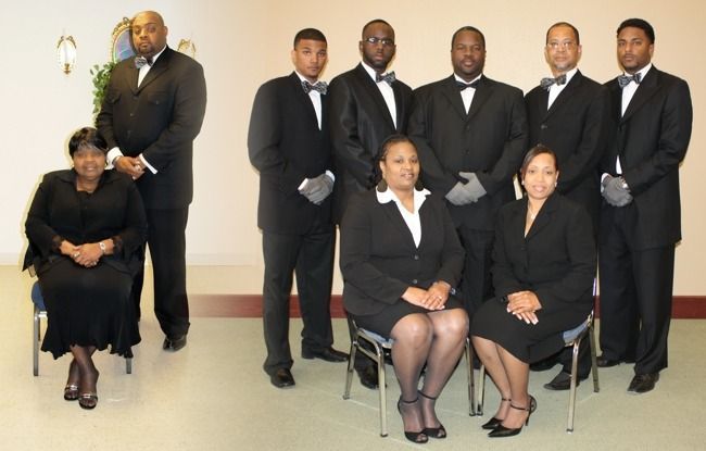 Group of people in formal attire, likely funeral home staff.