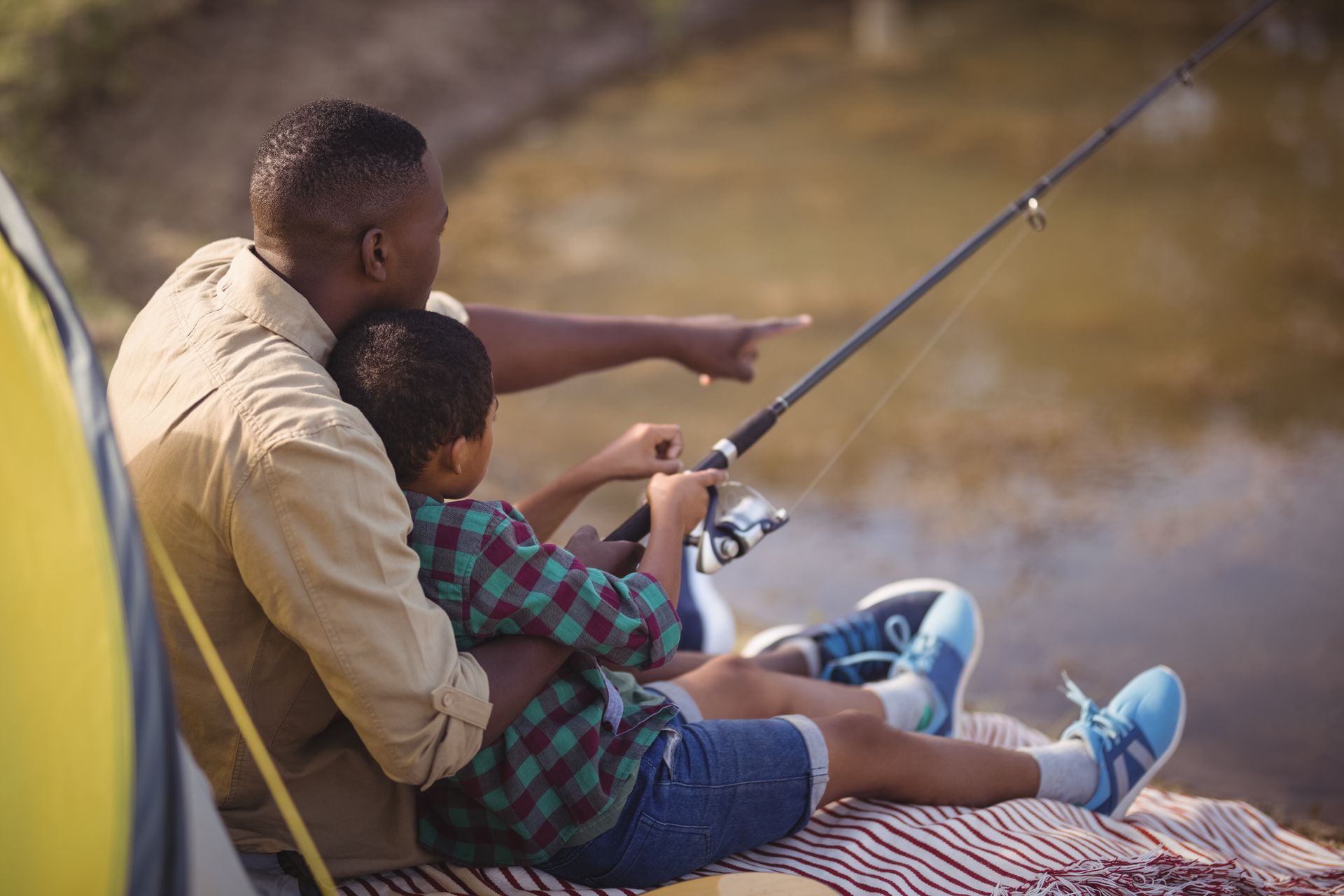 Man and child fishing, pointing at water.