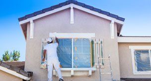 Exterior Re-Painting — Worker painting window outside the house in Carson City, NV