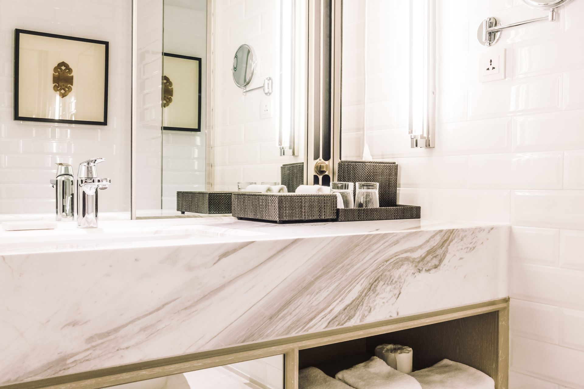 White marble bathroom vanity with sink, mirror, and toiletries.