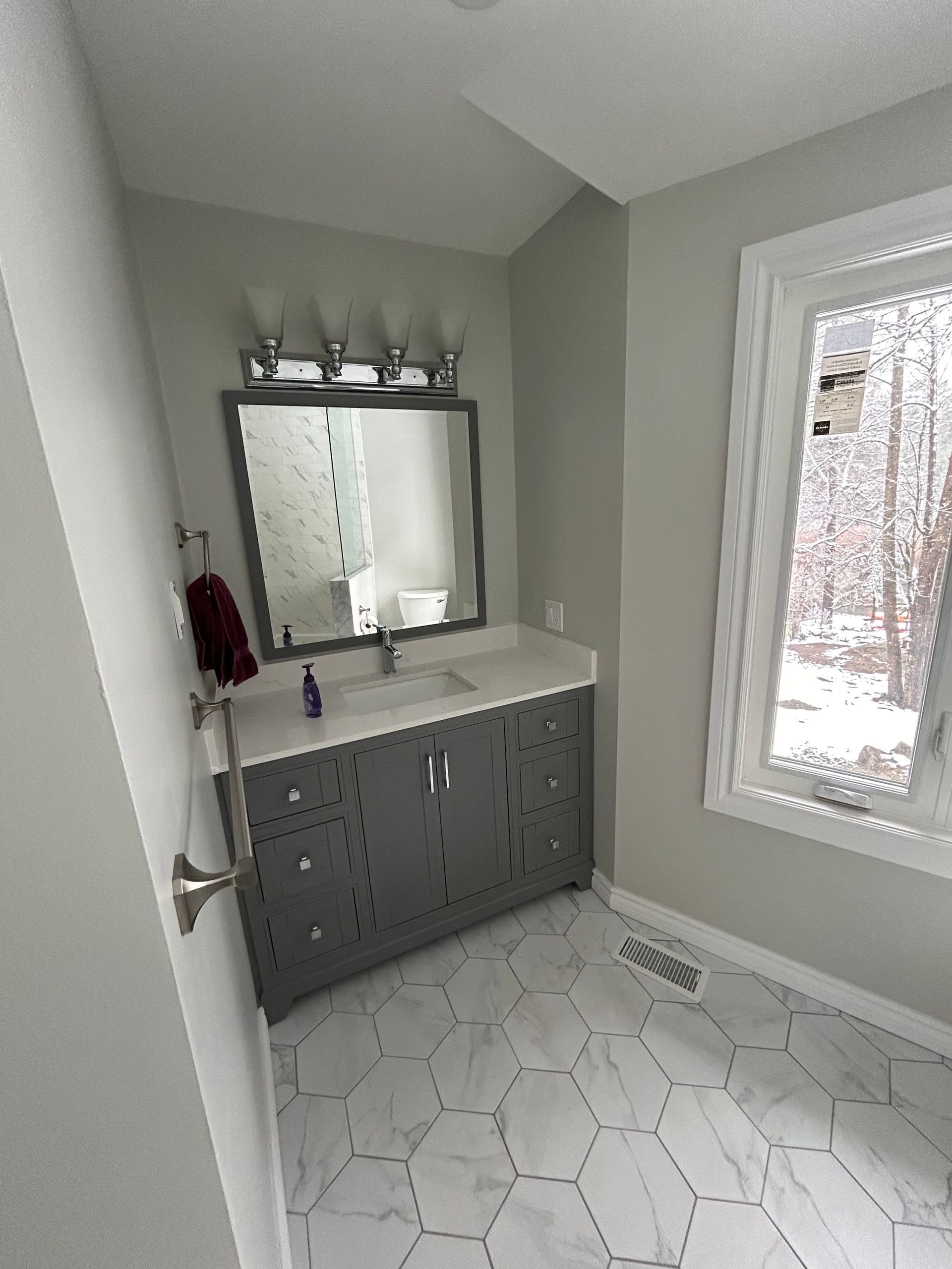 A bathroom with a sink , mirror and window.