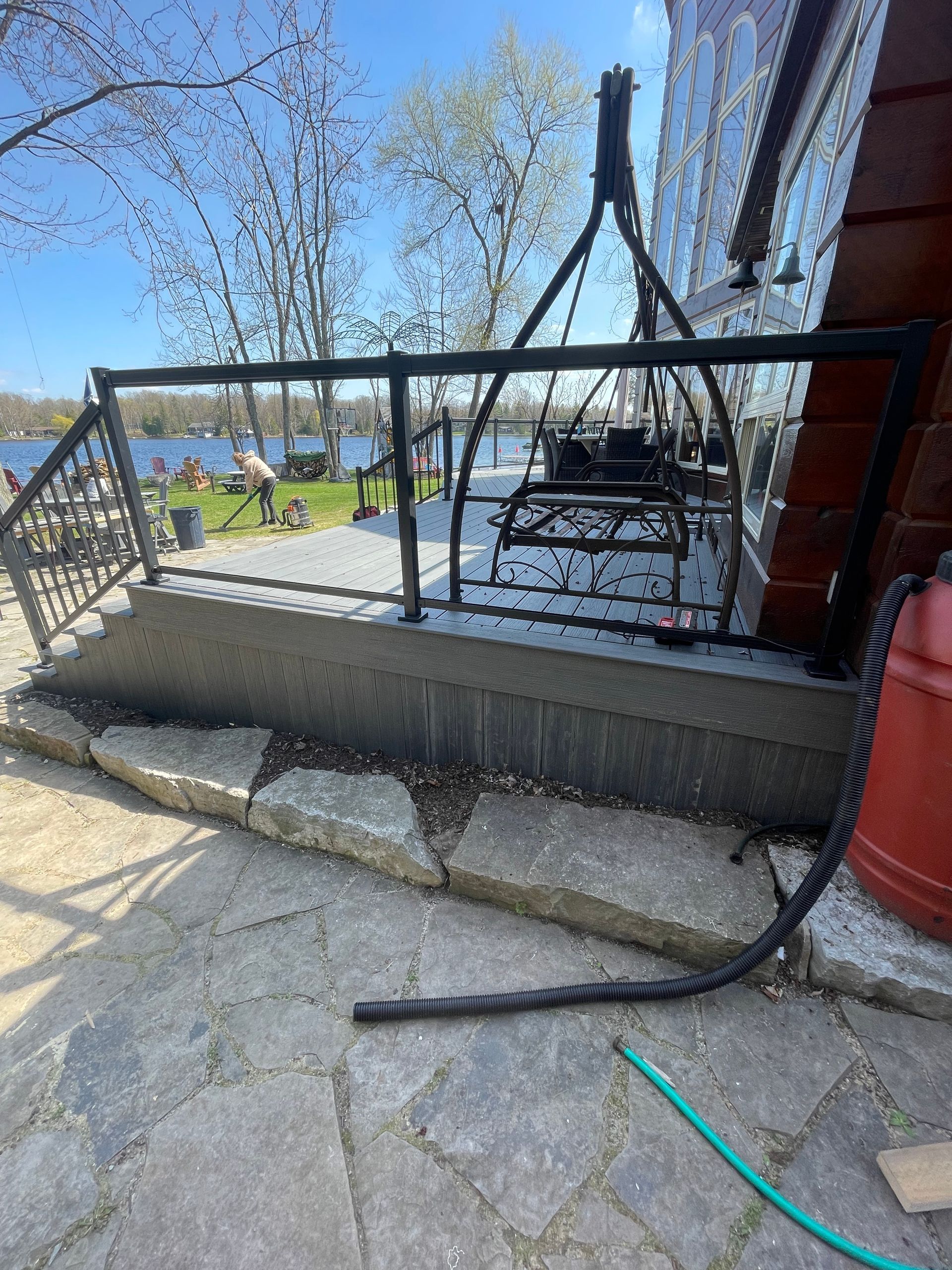 A hose is attached to a railing on a patio next to a house.