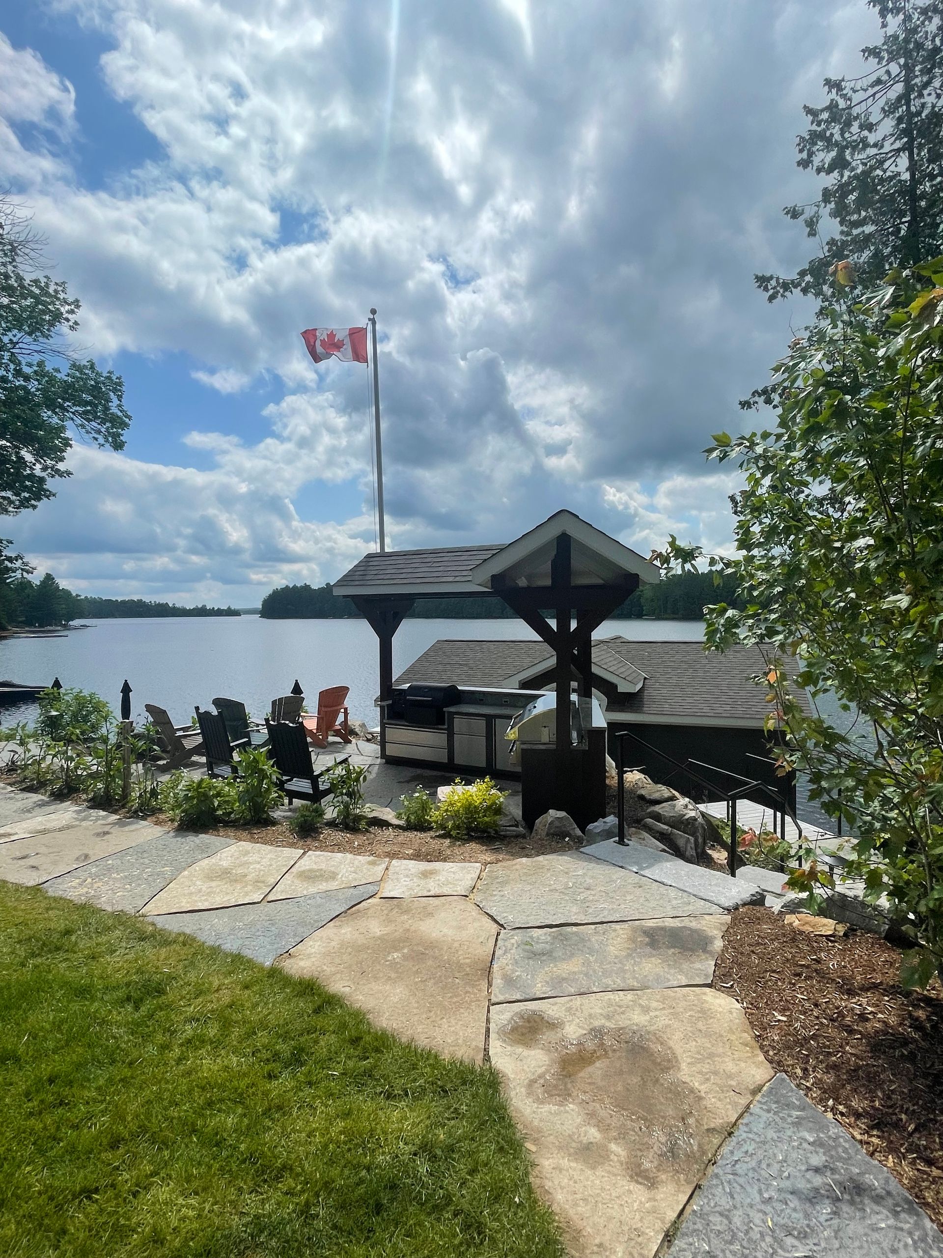 A canadian flag is flying over a dock next to a lake.